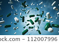 Falling pills green and white capsules against blue background, pharmaceuticals or health supplements. Pharmacist Day and pharmaceutical industry, World Health Day. Banner with copy space 112007996