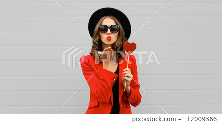 Beautiful stylish woman blowing kiss with sweet red heart shaped lollipop 112009366