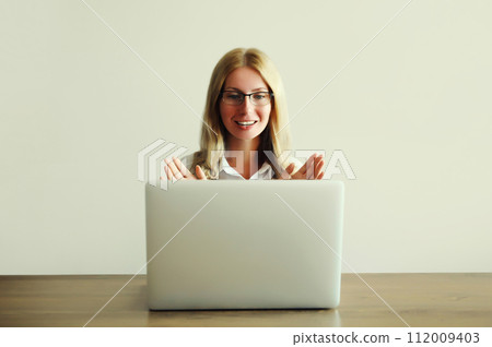 Woman working on laptop greets communicates with friends via video call Woman working on laptop greets communicates with friends via video call 112009403