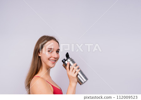 Image of beautiful strong happy cheerful young sports woman posing isolated indoors drinking water. Image of beautiful strong happy cheerful young sports woman posing isolated indoors drinking water. 112009523
