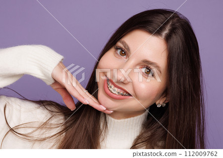 portrait of a girl with braces, woman happy with braces shows ok sign 112009762