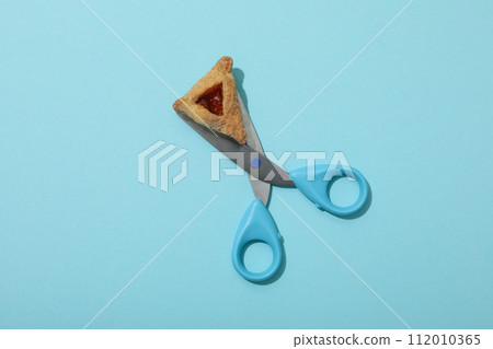 Scissors with traditional cookies, on a blue background. 112010365