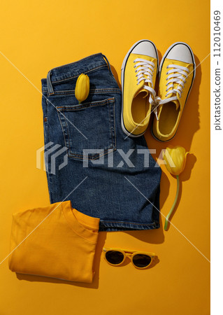 Female spring outfit and flowers on yellow background, top view 112010469