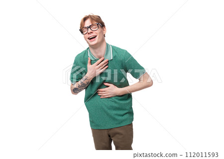 young red-haired man dressed in a green t-shirt laughs because of a joke young red-haired man dressed in a green t-shirt laughs because of a joke 112011593