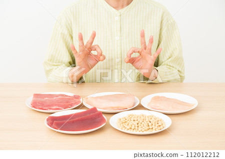 A middle-aged woman making a circle sign with foods high in protein 112012212