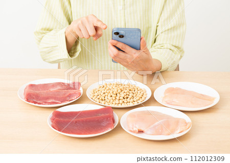 Middle-aged woman using protein-rich ingredients and smartphone 112012309