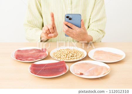 Middle-aged woman using protein-rich ingredients and smartphone 112012310