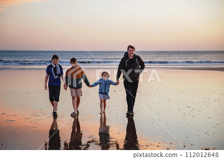 Portrait silhouettes of three children and dad happy kids with father on beach at sunset. happy family, Man, two school boys and one little preschool girl. Siblings having fun together. Bonding 112012648