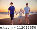 Three kids silhouettes running and jumping on beach at sunset. happy family, two school boys and one little preschool girl. Siblings having fun together. Bonding and family vacation. 112012650