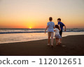 Three kids silhouettes running and jumping on beach at sunset. happy family, two school boys and one little preschool girl. Siblings having fun together. Bonding and family vacation. 112012651