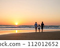 Three kids silhouettes running and jumping on beach at sunset. happy family, two school boys and one little preschool girl. Siblings having fun together. Bonding and family vacation. 112012652