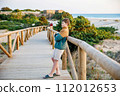 Happy cheerful teenager standing on beach at sunset. happy preteen handsome boy smiling at the camera. Kid on family vacation at the sea. 112012653