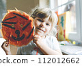 Little preschool girl painting with finger colors making animal tiger craft at home or nursery. Indoor activity with happy creative toddler child, homeschooling with parents 112012662