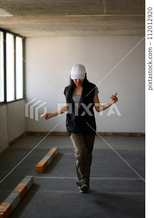 Shot of young woman practicing break dance or freestyle dance in parking garage 112012920