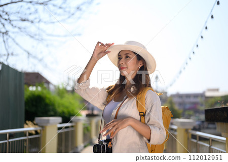 Beautiful young female tourist with backpack standing on bridge and enjoy scenery view of river 112012951