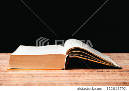 Open book on wooden and black background. The wisdom of generations, knowledge and love of reading, a place for text. 112013792