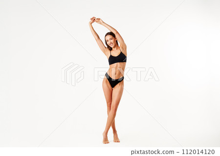 Full length portrait of smiling sporty woman in black underwear posing on white studio background Full length portrait of smiling sporty woman in black underwear posing on white studio background 112014120