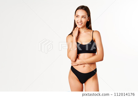 Pretty smiling woman in black underwear posing on white studio background Pretty smiling woman in black underwear posing on white studio background 112014176