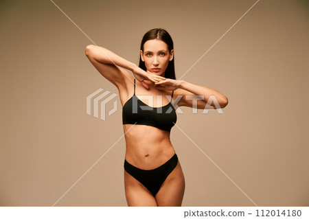 Sensual slim woman in black underwear posing on beige studio background 112014180