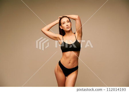 Sensual sporty young woman in black underwear posing with arms up 112014193