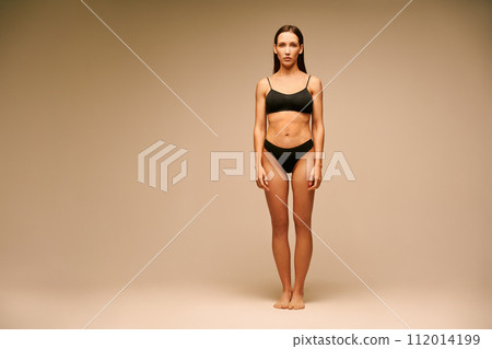 Pretty sporty woman in black underwear posing on beige studio background 112014199