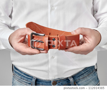 Terracotta leather belt with custom DAD embossing in male hands Terracotta leather belt with custom DAD embossing in male hands 112014385