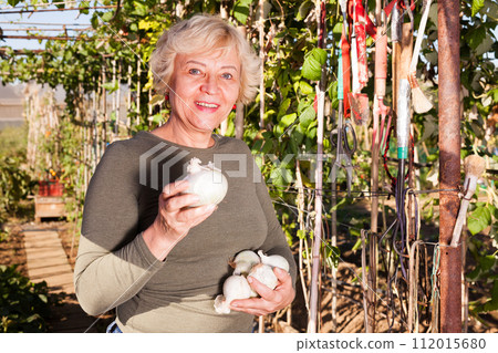 Woman showing onion in garden Woman showing onion in garden 112015680