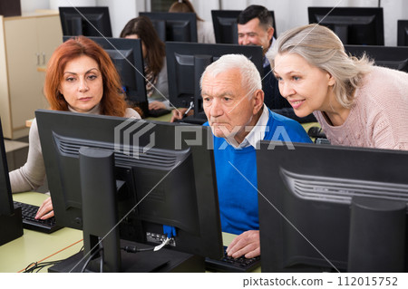Three coworkers working around computer monitor, talking about new project 112015752