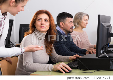 Young female teacher explaining computer skills to mature woman Young female teacher explaining computer skills to mature woman 112015771
