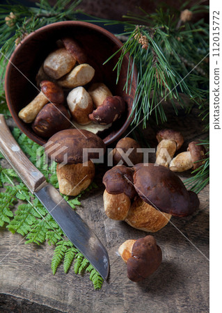 Imleria Badia or Boletus badius mushrooms commonly known as the bay bolete, clay bowl with mushrooms and knife on vintage wooden background.. 112015772
