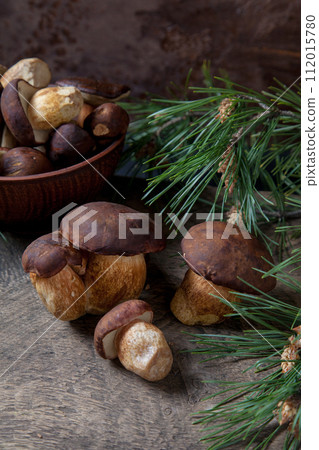 Imleria Badia or Boletus badius mushrooms commonly known as the bay bolete and clay bowl with mushrooms on vintage wooden background.. 112015780