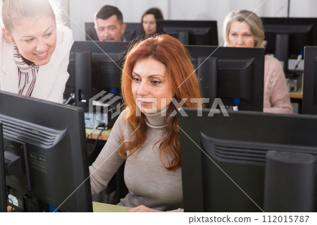 Young female teacher explaining computer skills to mature woman Young female teacher explaining computer skills to mature woman 112015787