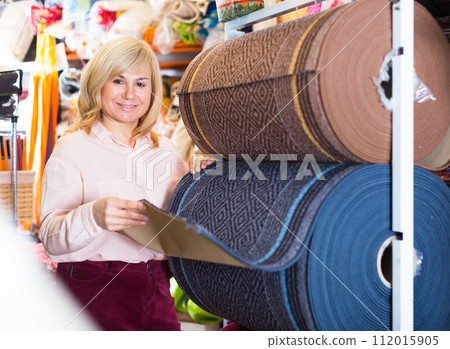 Woman choosing carpeting to her new house interior 112015905