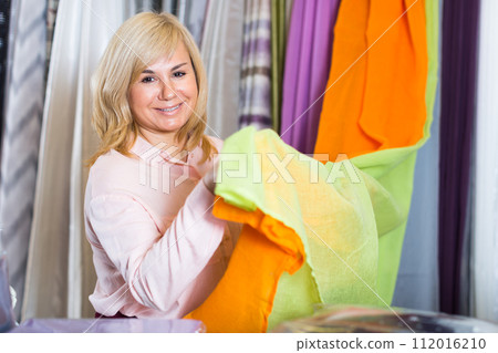 Mature woman customer choosing color curtains Mature woman customer choosing color curtains 112016210