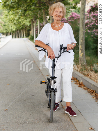 Senior woman resting near bike 112016590