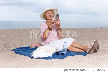 Elderly woman using phone at seaside Elderly woman using phone at seaside 112016597