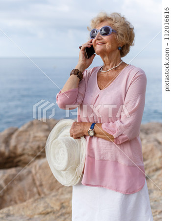 Aged woman talking on phone outdoors 112016616
