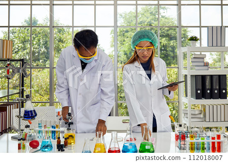 Two Scientists Conducting Research analyzing chemical experiments in Laboratory 112018007