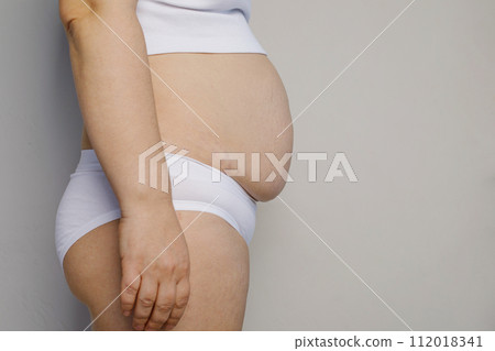 Big female stomach with stretch marks, profile. Woman stomach belly fat closeup. Overweight, fatness Big female stomach with stretch marks, profile. Woman stomach belly fat closeup. Overweight, fatness 112018341