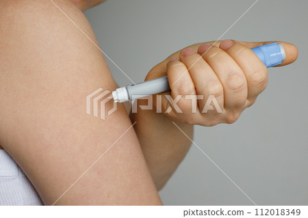 Blue self injection pen near female shoulder. Medicine and treatment concept Blue self injection pen near female shoulder. Medicine and treatment concept 112018349