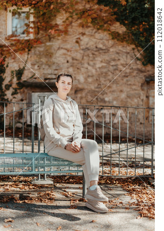 Attractive young woman sitting on a bench enjoying a view of medieval town in Europe. Summer holidays concept. 112018642