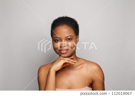 Cute healthy young woman with dark shiny skin smiling looking at camera on white background. 112019067