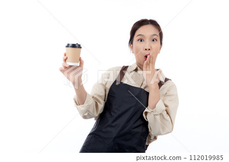 Cheerful young asian woman barista in casual work attire happily holding a takeaway coffee cup. Cheerful young asian woman barista in casual work attire happily holding a takeaway coffee cup. 112019985