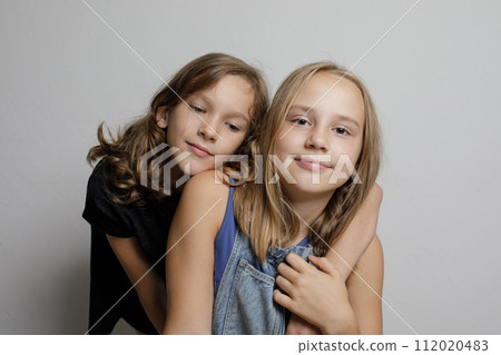 Sweet children sisters friends hugging on white studio wall banner background, fashion portrait Sweet children sisters friends hugging on white studio wall banner background, fashion portrait 112020483