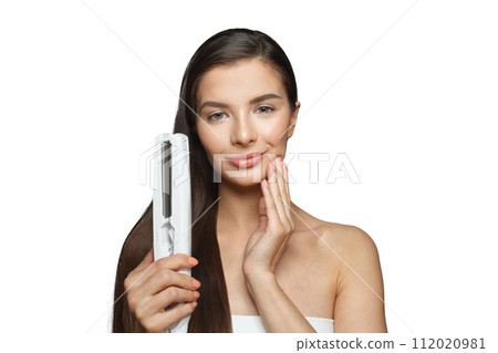 Gorgeous model woman holding hair iron and straightening her healthy long dark hair isolated Gorgeous model woman holding hair iron and straightening her healthy long dark hair isolated 112020981