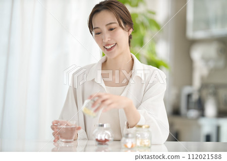 Woman drinking supplements in the living room 112021588