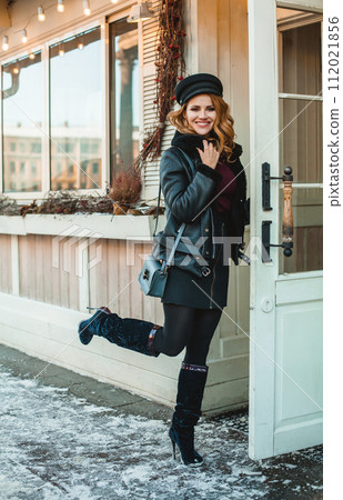 Beautiful glamorous brunette woman in black leather jacket and black hat standing near shop door Beautiful glamorous brunette woman in black leather jacket and black hat standing near shop door 112021856