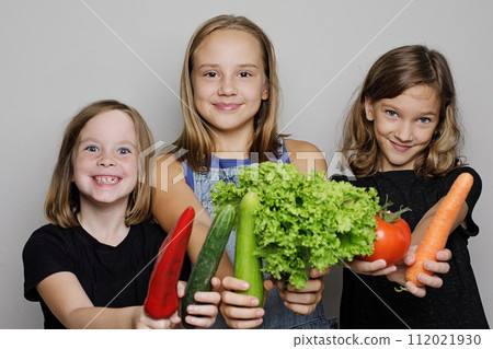 Portrait of beautiful children holding vegetables on white studio wall banner background. 112021930