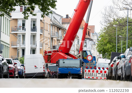 Extra heavy weight load mobile boom crane working on narrow european old city street background. Telescopic boom lifting equipment construction site rental service. Heavy industrial machinery 112022230