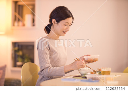 一位女商人的夜間例行公事，用準備好的菜餚吃晚餐 112022334